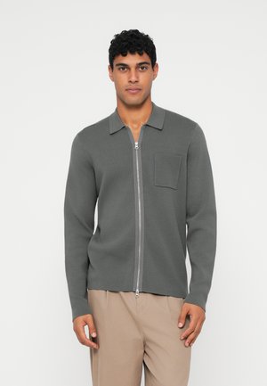 Grå stickad cardigan med zip-fram, krage, långa ärmar och en bröstficka. Slät textur med en avslappnad passform.