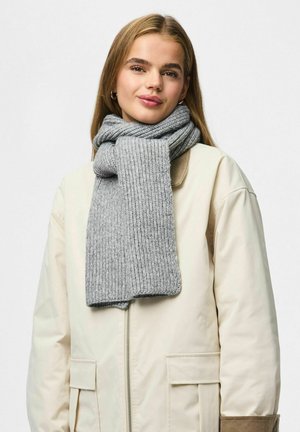 Écharpe grise côtelée en matériau doux, avec un design large et une texture lisse, drapée autour du cou sur une veste beige.