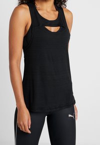 Svart atletisk linne med lagerdesign och urtaget detalj vid halsringningen, tillverkat av ett mjukt, lätt tyg.