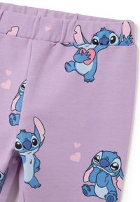 Paarse legging gemaakt van zachte stof met gedrukte blauwe Stitch-personages en verspreide lichtroze harten. Elastische tailleband voor comfort.