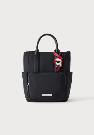 Sac fourre-tout noir avec poche avant zippée et poignées courtes, avec un petit porte-clés cartoon rouge et blanc avec des lunettes de soleil.