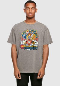 Grafisch oversized t-shirt in grijs, met een kleurrijk "ThunderCats" ontwerp waarin personages omringd zijn door vlammen en een prominent logo.