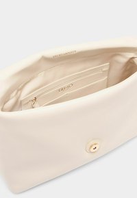 Beige tyghandväska insida med en jämn textur, utrustad med ett blixtlåsfack och kortfack, kompletterad med en knappstängning i guldton.