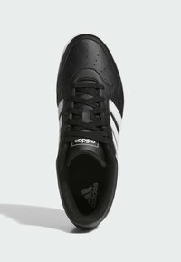 Zapato deportivo negro con una parte superior de cuero liso, tres rayas blancas, puntera perforada, cordones negros y un forro interior acolchado.