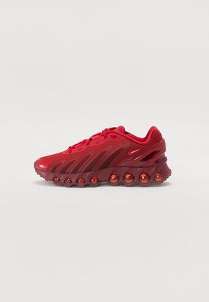 Baskets de sport rouges avec tige en mesh, semelle unique en forme de bulles et petit logo swoosh latéral, montrées de profil sur fond uni.