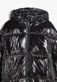 Shiny black puffer jacket with a hood, featuring quilted sections, dual front zippers, and textured surface for added visual interest.