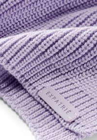 Țesătură tricotată de lavandă cu un model de ribbing pronunțat. Prezintă un etichetă de piele violet deschis cu inscripția "EXPATRIÉ" embosată și accente cusute.