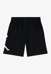 Schwarze Sportshorts aus atmungsaktivem Material. Verfügen über einen elastischen Bund und eine weiße Grafik am linken Bein.