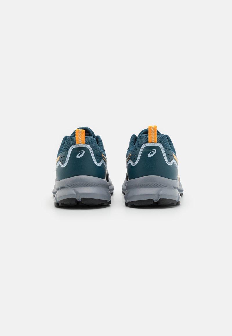 Baskets de sport teal avec une semelle grise, présentant un dessus texturé, une boucle au talon orange contrastante et des accents réfléchissants argentés.