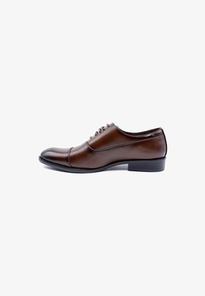 Chaussure habillée en cuir marron avec un bout arrondi, système de laçage fermé et un petit talon. Texture lisse avec un subtil détail de couture.