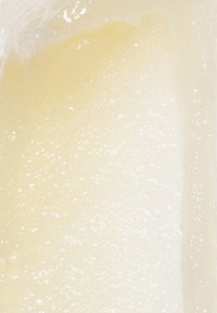 Close-up of pale yellow, smooth, and glossy gel or cream texture with small bubbles or sparkles throughout.