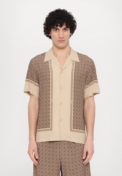 Chemise beige à manches courtes avec des motifs géométriques marron et une fermeture à boutons sur le devant. Texture lisse avec des rayures contrastantes sur les manches.
