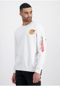 Biała bluza z kapturem z logo NASA w pomarańczowym kolorze na piersi. Posiada długie rękawy, ściągacze przy mankietach oraz kieszeń na rękawie z czerwoną taśmą.