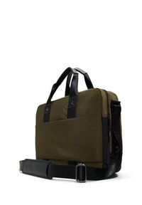 Olijfgroene canvas tas met zwarte leren accenten, dubbele handvatten aan de bovenkant, afneembare schouderband, ritssluiting en een buitenvak.
