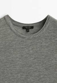 Graues Crewneck-T-Shirt aus weichem, strukturiertem Stoff. Verfügt über ein Etikett mit Größeninformationen. Die Farbe ist einfarbig mit einem subtilen Melange-Muster.