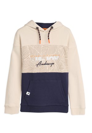 Sweat-shirt à capuche avec une partie supérieure beige ornée d'un motif de feuilles, une section inférieure marine, et une poche kangourou à l'avant. Les cordons de serrage sont de couleur orange.