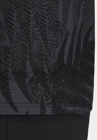 Svart tyg med en strukturerad mönster av mörka ormbunkar, vilket skapar en subtil kontrast mot den släta bakgrunden. Rektangulär form, ingen synlig hårdvara.