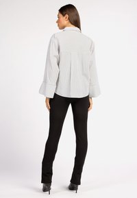 Gestreepte blouse met bell mouwen in lichtgrijs en wit. Gecombineerd met zwarte nauwsluitende broek en hoge hakken.