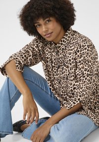 Camicia a maniche lunghe con stampa leopardata in tessuto morbido e leggero. Presenta un colletto, maniche ampie e una vestibilità comoda; abbinata a jeans azzurri chiari.