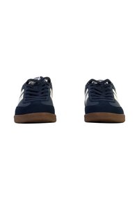 Zapatillas deportivas de color azul marino con acentos blancos, material de ante, puntera redonda, suela de goma y cordones planos. Diseño simple con detalles mínimos.