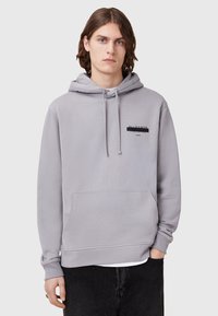 Lichtgrijze hoodie van zachte stof, met een vooraanstaande kangoeroezak, een capuchon met trekkoord en een geborduurd merkembleem op de borst.