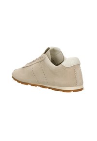 Béžové semišové tenisky s kulatou špičkou, šněrováním na přední straně a texturovaným bílým akcentem na patě. Mají jemné prošívání po stranách.