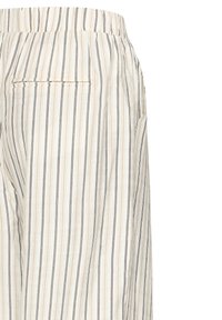Beżowe i białe spodnie z cienkimi, pionowymi czarnymi i brązowymi paskami, wyposażone w pasek w talii i tylną kieszeń z patką.