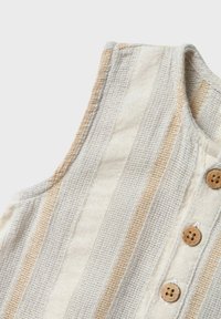 Randig linnetopp i creme och beige, med en texturerad väv och träknappar längs framknäppningen.