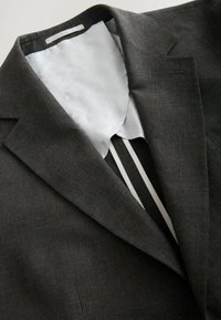 Sacou cu carouri în nuanțe de maro închis, cu o căptușeală interioară albă și gri, având un guler clasic în formă de v și un design minimalist.