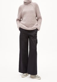 Ljusrosa ribbad polotröja kombinerad med lösa svarta cargobyxor och canvas sneakers med zebramönster. Mjukt material och avslappnad passform.