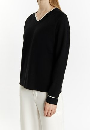Zwarte V-hals trui met contrasterende lichtgrijze afwerking bij de halslijn en mouwen, met een zachte textuur en een relaxte pasvorm.