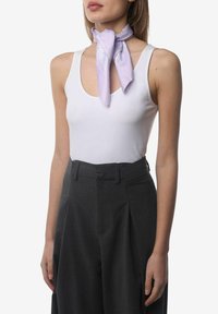 Débardeur blanc à encolure dégagée associé à un pantalon taille haute gris foncé. Une écharpe violet clair est nouée autour du cou, ajoutant un contraste.