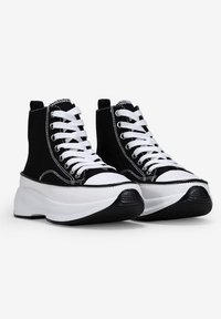 Sneakers alte in tela nera con lacci bianchi, suola bianca a contrasto e punta in gomma nera. Presentano dettagli in cucitura bianca.