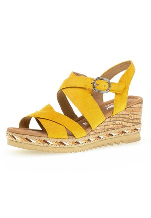 Gul ruskind kilehæl sandal med krydsede stropper, sølvspænde, korktekstureret platform og flettet detalje på sålkanten.
