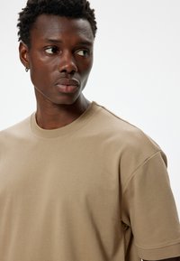 Tanskleurig katoen t-shirt met een ronde hals, korte mouwen en een soepele textuur. Eenvoudig ontwerp zonder patronen of accenten.
