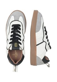 Sneaker bianchi e grigi con tomaia in pelle liscia, lacci neri e suola in gomma color cuoio. Il design distintivo include dettagli cuciti.
