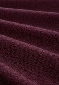 Tissu tricoté en bourgogne profond, présentant une texture lisse avec des motifs de côtes subtils et des plis longs et doux.