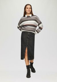 Pull gris et blanc à rayures avec un col rond, associé à une jupe en denim noire avec une fente à l'avant et des bottes de combat noires.