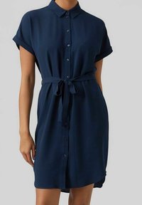 Vestito camicia blu navy con colletto, maniche corte arrotolate, chiusura davanti con bottoni e vita legata. Tessuto morbido con taglio rilassato.