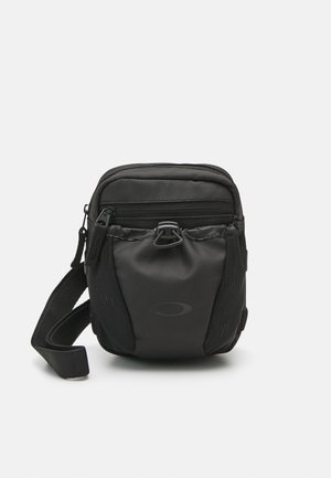 Zwarte nylon schoudertas met ritscompartimenten, gestructureerde oppervlakte, verstelbare band en logo detail aan de voorkant. Compact ontwerp.