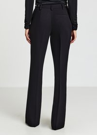 Schwarze Hose mit maßgeschneiderter Passform, flacher Vorderseite, seitlichen Taschen und einer glatten, eleganten Textur. Keine sichtbaren Muster oder Akzente.