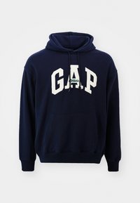 Felpa con cappuccio blu navy realizzata in cotone, dotata di tasca frontale, con logo bianco "GAP" e cappuccio regolabile, texture morbida e polsini a coste.