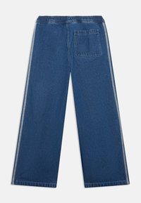 Σκούρο μπλε τζιν παντελόνι με φαρδιά μπάτζια και ελαστική μέση, με μία πίσω τσέπη και αντίθετες ρίγες στα πλαϊνά. Υφασμένο από υφή denim με λείο φινίρισμα.