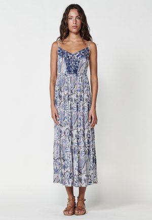 Blauwe en witte maxi-jurk met patroon en dunne schouderbandjes, met een aansluitend lijfje en een vloeiende, gelaagde rok. Getextureerd bloemmotief.