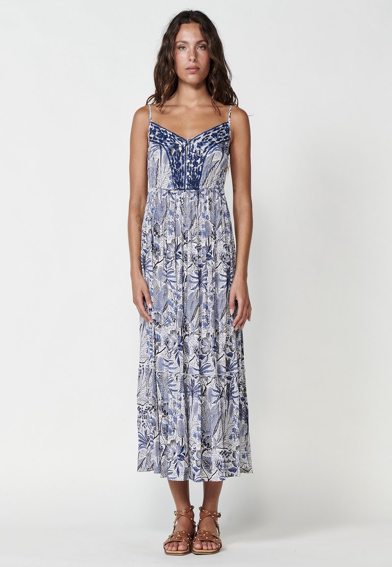 Rochie maxi cu un model albastru și alb, cu bretele subțiri, având un bust ajustat și o fustă fluidă în straturi. Design floral texturat.
