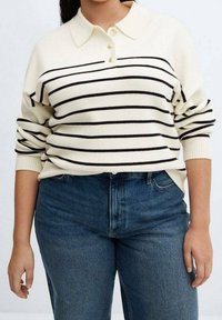 Pull en tricot couleur crème avec des rayures horizontales noires, col polo et trois boutons. Associé à un jeans en denim bleu taille haute.