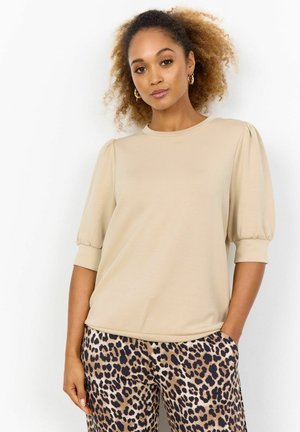Beige short-sleeve top with gathered sleeves, paired with brown animal-print pants. Smooth fabric and relaxed fit.