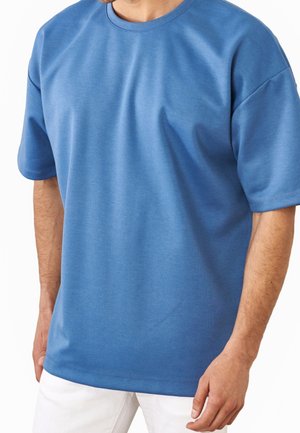 Blå bomulds-T-shirt med korte ærmer, rund halsudskæring og en afslappet pasform. Glat tekstur med minimale syninger og uden mønstre.