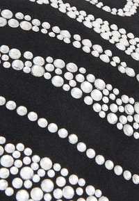 Musta kangas, jossa koholla olevia rivejä erikokoisia kirkkaita strasseja aaltomaisessa kuviossa, luoden tekstuuria ja kontrastia.