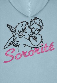 Svetlomodrá mikina s čiernym vyšitím dvoch cherubov, ktorí sa objímajú, a pod nimi je v ružovej kurzíve nápis "Sororité".